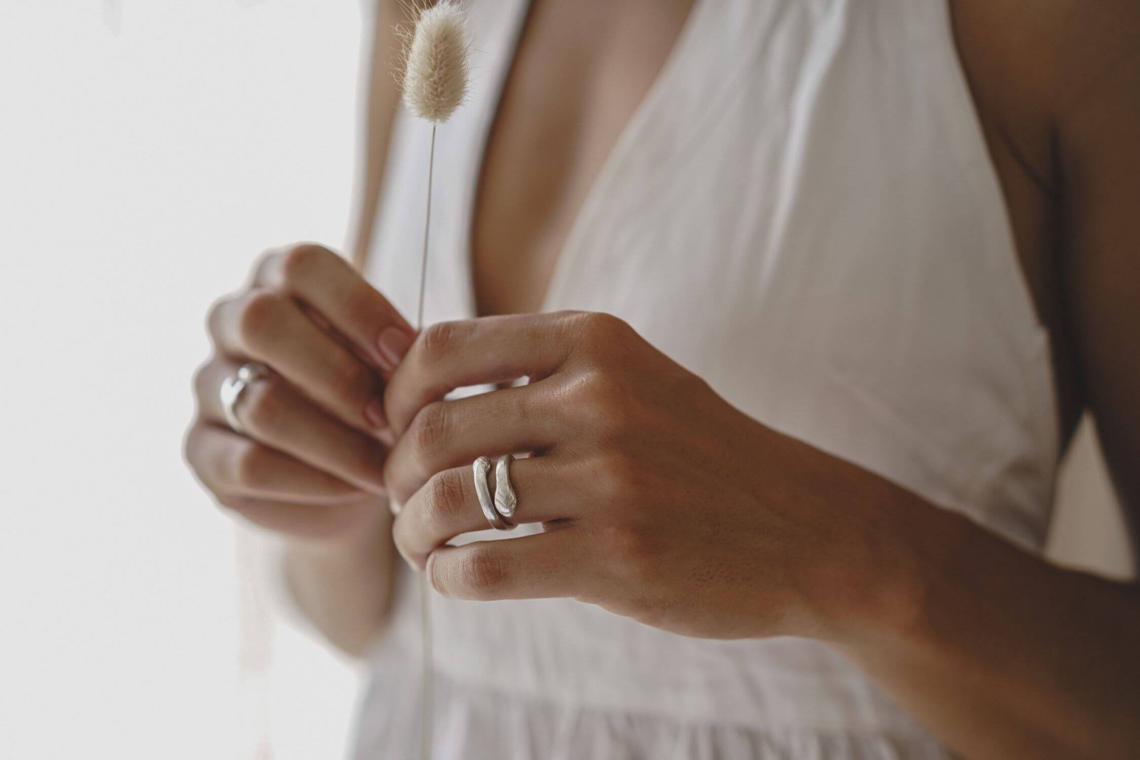 Woman with silver rings wearing white dress.